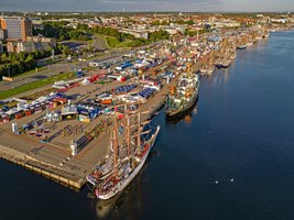 Luftaufnahme von Stadthafen Rostock. Viele Schiffe liegen am den Hafenkanten und auf Freiflächen sind Jahrmarktstände aufgebaut