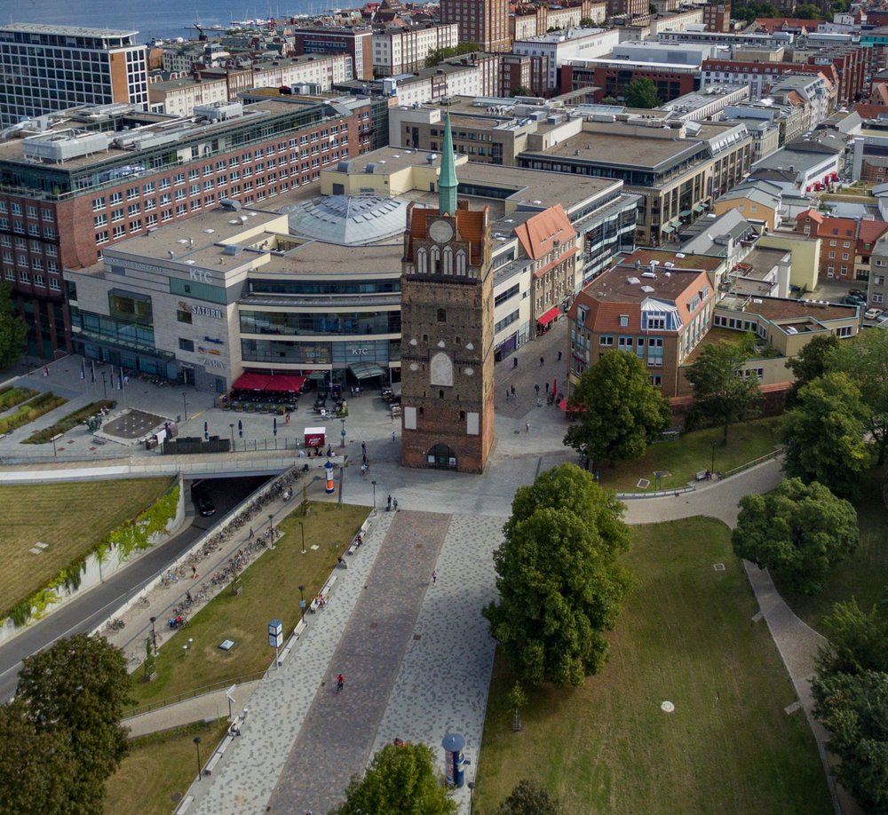Luftaufnahme des Kröpeliner Tors mit dem Vorplatz. Im Hintergrund die Rostocker Innenstadt mit Fluss Warnow 