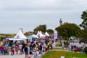 Viele Personen auf Warnemünder Promenade mit Jahrmarktzelten