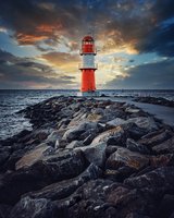 Rot Weiß gestreifter Leuchtturm mit Mole bei Sonnenuntergang mit Rot grauen Wolken